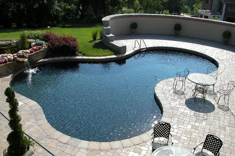 A freeform Sequoyah pool with a rock water feature and mature planting.